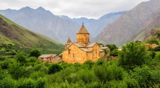 Monastère arménien ancien niché dans une vallée verdoyante avec montagnes du Caucase en arrière-plan